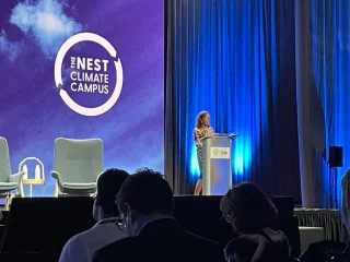 Ceres CEO Mindy Lubber stands on a stage addressing a crowded room at the Nest Climate Campus at Climate Week in New York City.